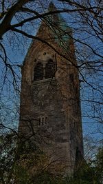 Low angle view of bare tree against built structure