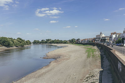 Scenic view of river amidst buildings against sky