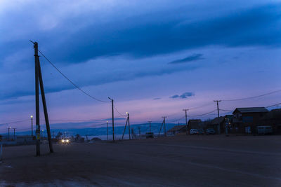 Street by sea against sky at sunset