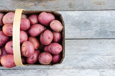 Close-up of potatoes in basket on wooden table