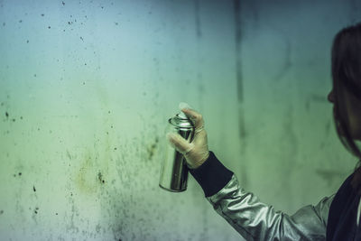 Side view of woman spray painting on wall