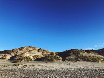 Scenic view of arid landscape against clear blue sky