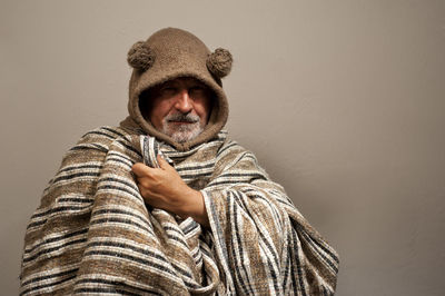 Portrait of man wearing hat sitting against wall