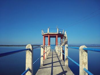 Lifeguard hut by sea against clear blue sky