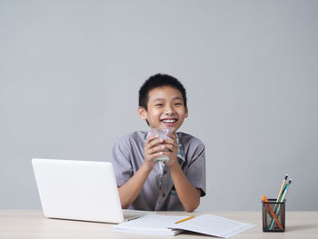 Portrait of smiling young woman using phone while sitting on table