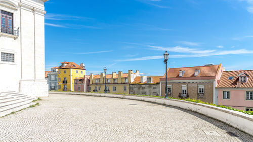 Street amidst buildings against blue sky