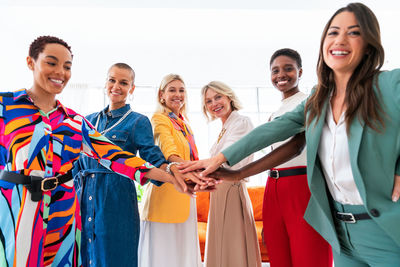 Portrait of smiling friends standing against wall