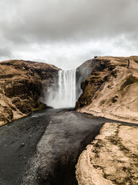 Scenic view of waterfall against sky