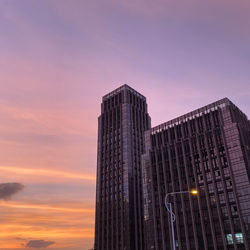 Low angle view of illuminated buildings against sky at sunset