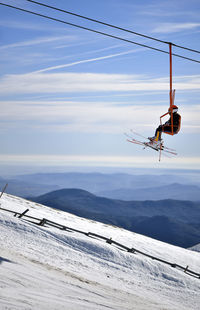 Man sitting on overhead cable car in mountains