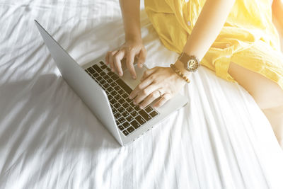 Midsection of woman using mobile phone on bed