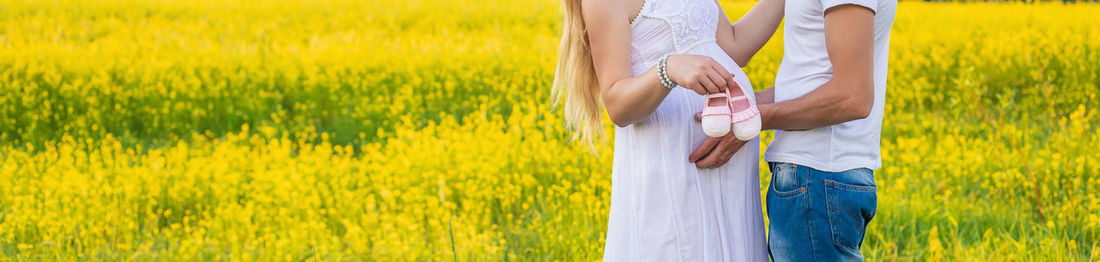 Midsection of man with pregnant wife holding baby booties