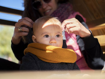 Close-up of cute girl wearing sweater and knit hat sitting with mother at home