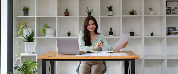 Portrait of young woman using laptop at home