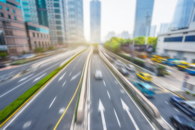 Blurred motion of vehicles on road amidst buildings in city