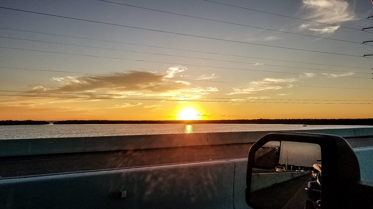 CAR ON SEA AGAINST SUNSET SKY