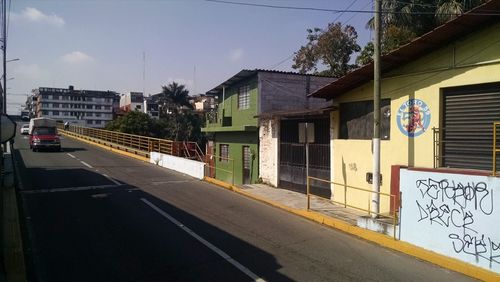 Road by houses against sky