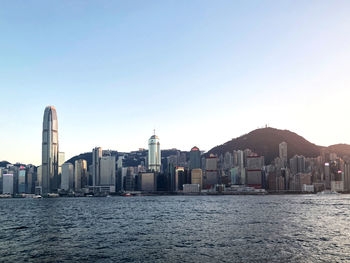 Sea by modern buildings against clear sky