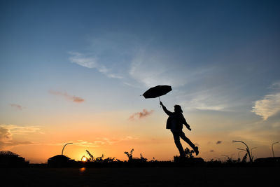 Silhouette people playing on street against sky during sunset