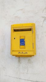 Yellow letterbox mounted on wall