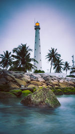 Lighthouse by sea against sky