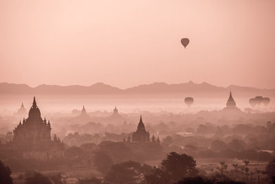 Hot air balloons over foggy landscape against sky