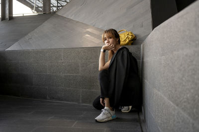 Portrait of businesswoman crouching on floor by wall