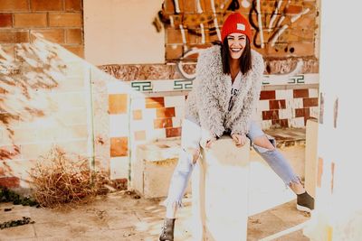 Portrait of young woman standing against building