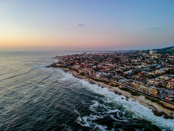 High angle view of sea and buildings against sky during sunset