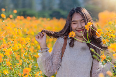 Smiling woman standing by yellow flowering plants