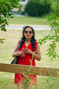 Young woman with red umbrella standing on field