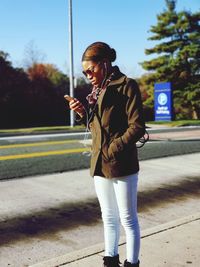 Mature woman using mobile phone while standing on road
