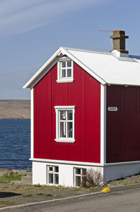 Small  house with attic and basement and red corrugated metal facade with a view of the fjord