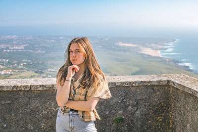 Portrait of young woman standing against sea