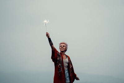 Low angle view of person holding umbrella against sky