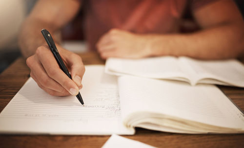 Midsection of woman writing in book