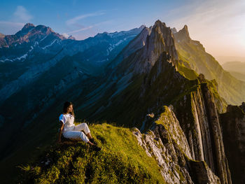 Woman sitting on rock against mountains