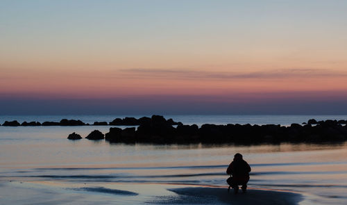 Silhouette woman standing on beach against sky during sunset