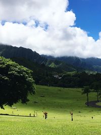 People on field by mountains against sky