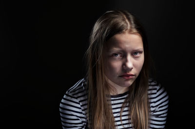 Close-up portrait of girl against black background