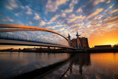 Bridge over river against cloudy sky