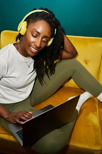 Black styled student woman listening music with yellow earphones