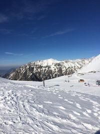 Snow covered landscape against blue sky