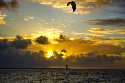 Silhouette person in sea against sky during sunset