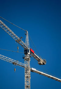 Low angle view of crane against clear blue sky