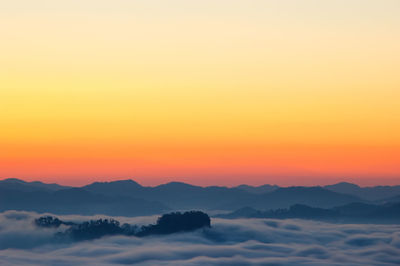 Scenic view of silhouette mountains against orange sky