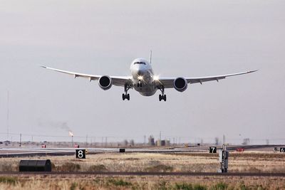 Airplane flying over airport runway against sky