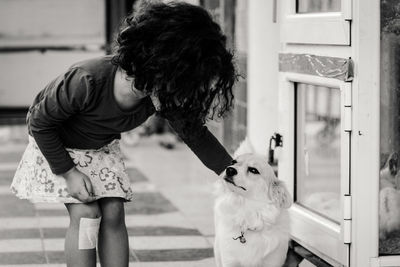 Girl stroking dog by window