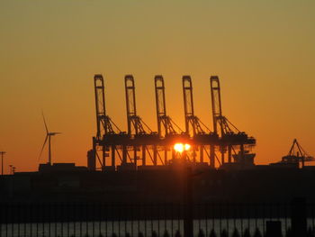 Silhouette cranes against clear sky during sunset