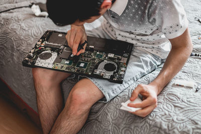 A young man is changing the thermal paste on a laptop.